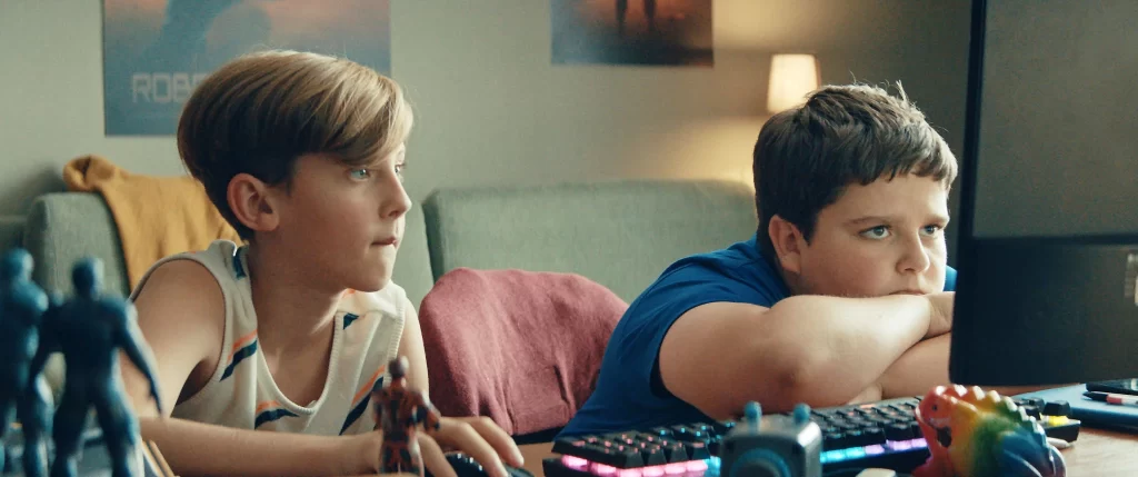 Na zdjęciu dwoje chłopców siedzący przy komputerze. Kadr z filmu.