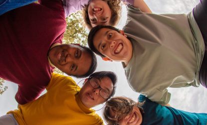 Zdjęcie przedstawia grupę osób uśmiechających się, nachylających się nad aparatem. Zdjęcie kolorowe i wesołe.