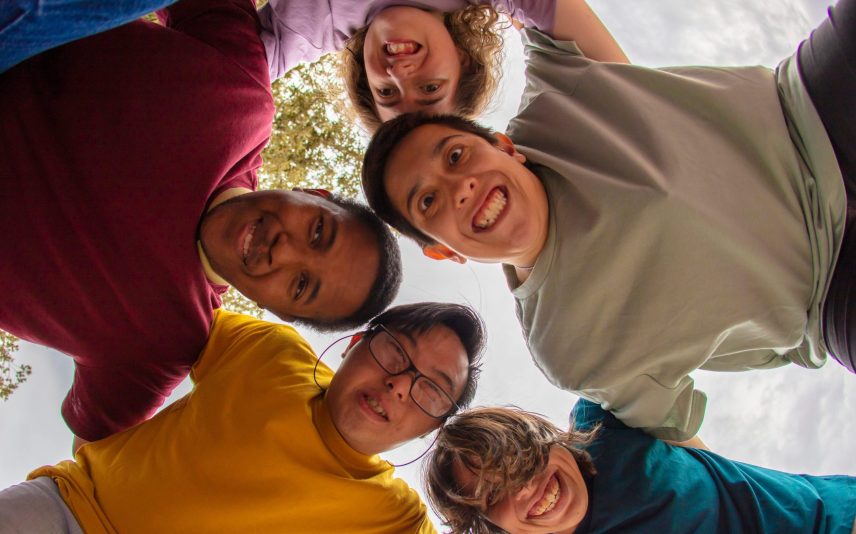 Zdjęcie przedstawia grupę osób uśmiechających się, nachylających się nad aparatem. Zdjęcie kolorowe i wesołe.